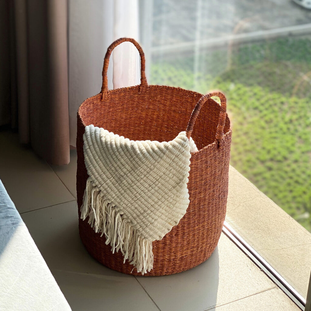 a woven laundry basket with a blanket on it